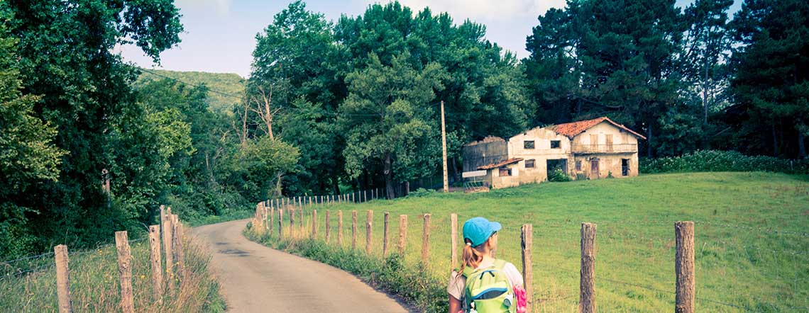 pilgrim walking on rural road by house in country