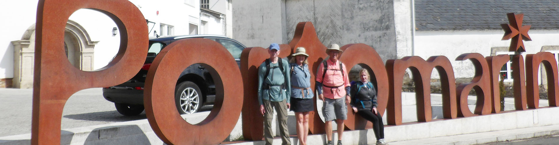 pilgrims standing by Camino sign in Portomarin
