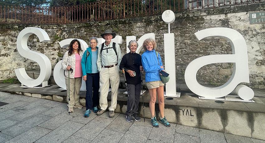 pilgrims standing by Sarria sign