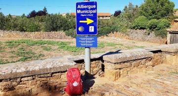 backpack by albergue sign on the camino from leon