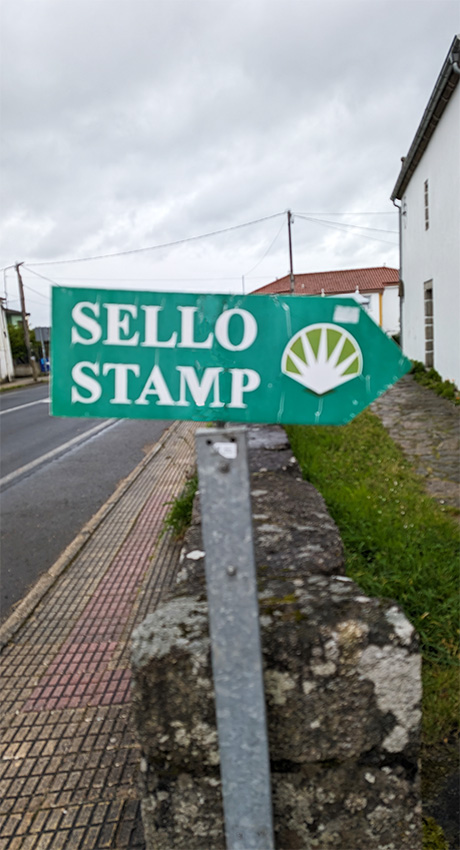 sign pointing the way to where stamps can be obtained in the Camino