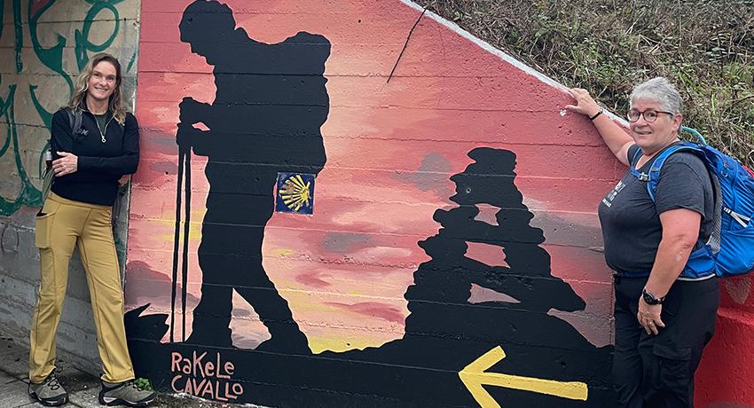 pilgrims by a handpainted mural on the Portuguese Camino