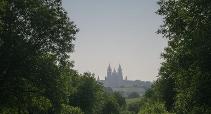 pilgrims staring at eclipse in the sky with Santiago's cathedral on the horizon