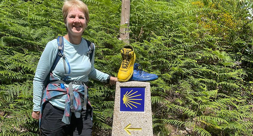 pilgrim by Camino marker with boots